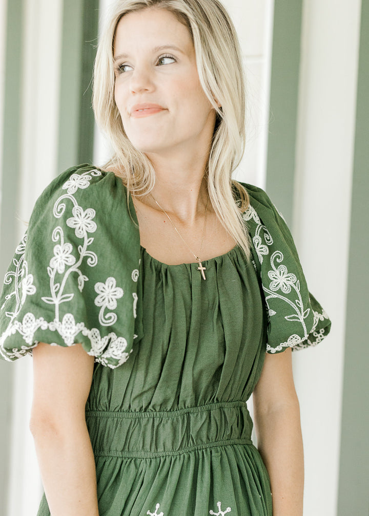 Close up of pleated bodice, bubble short sleeves and elastic waist on hunter green dress. 