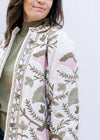 Close up of pink and green embroidered flowers on a cream long sleeve jacket with an open front. 