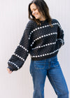 Model wearing a black sweater with white striped dots and bubble long sleeves.