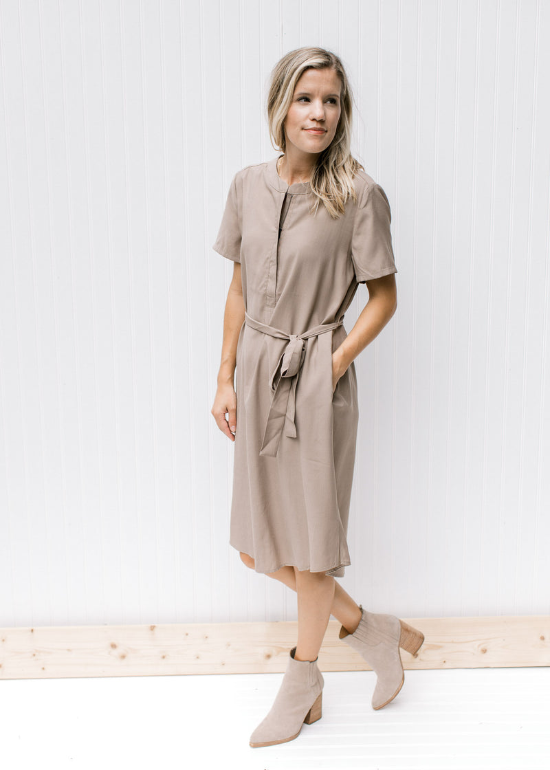 Model wearing booties with a taupe knee length dress with a hidden front zipper and short sleeves. 