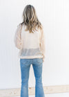 Back view of Model wearing a cream open weave sweater with a round neck and long sleeves.