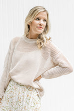 Model wearing a cream open weave sweater with long sleeves and a round neck.
