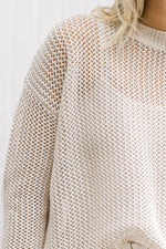 Close up view of Model wearing a cream open weave sweater with long sleeves and a round neck.