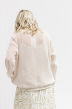 Back view of Model wearing a cream open weave sweater with long sleeves and a round neck.