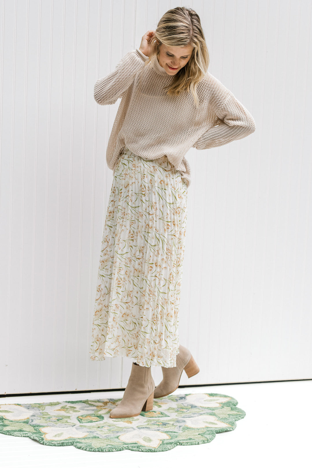 Model wearing a floral skirt with a cream open weave sweater with long sleeves and a round neck.