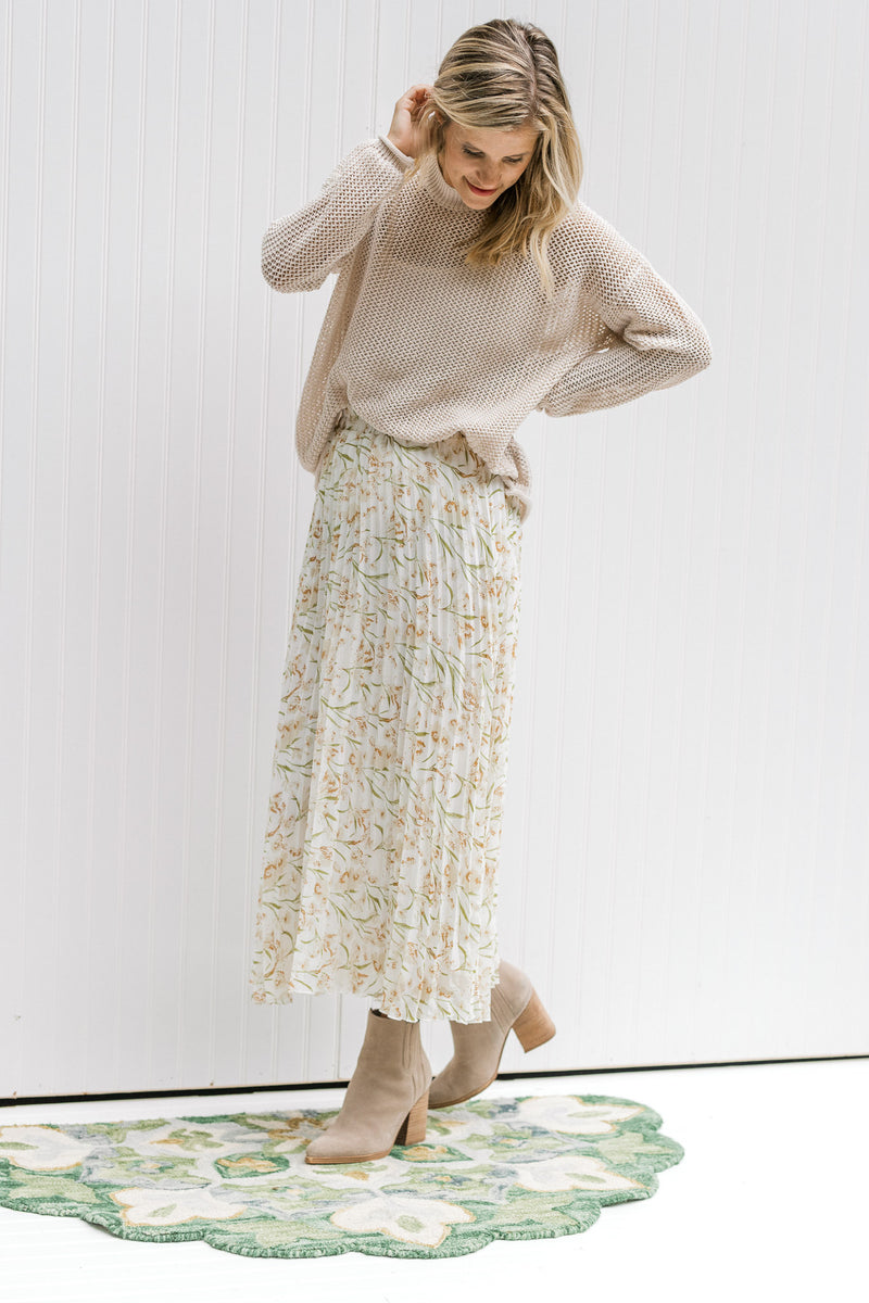 Model wearing a floral skirt with a cream open weave sweater with long sleeves and a round neck.