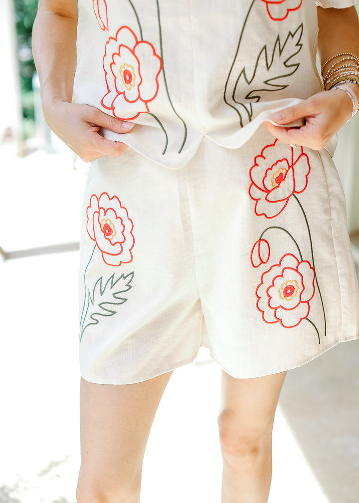 Model wearing a cream shorts set with orange embroidered floral with 3” inseam shorts. 