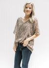 Model wearing a sage v-neck top with a tan paisley print and batwing sheer short sleeves. 