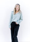 Model wearing a pale blue sweater with an exaggerated collar, long sleeves and a v-neck. 