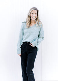 Model wearing a pale blue sweater with an exaggerated collar, long sleeves and a v-neck. 