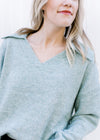 Close up of exaggerated collar and v-neck on a pale blue sweater with long sleeves. 