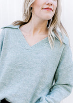 Close up of exaggerated collar and v-neck on a pale blue sweater with long sleeves. 