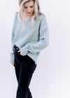 Model wearing black pants and a pale blue sweater with a collar, long sleeves and a v-neck. 