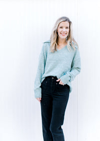 Model wearing a cozy pale blue sweater with an exaggerated collar, long sleeves and a v-neck. 