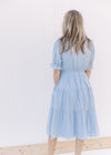 Back view of Model wearing a pale blue midi with ruffle v-neck and ruffle poet short sleeves.