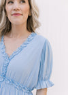 Close up of poet short sleeves and ruffle at v-neck on a pale blue midi dress. 
