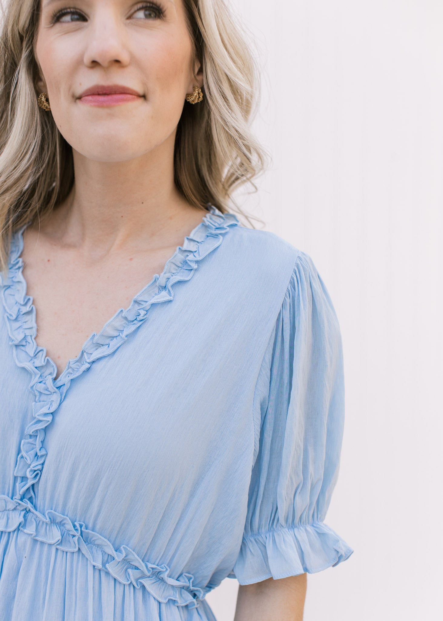 Close up of poet short sleeves and ruffle at v-neck on a pale blue midi dress. 