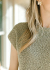 Close up of knit fabric and round neck on a pale sage sweater with capped sleeves. 