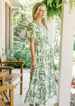 Model wearing a cream dress with green palm leaves, elastic waist and bubble short sleeves. 