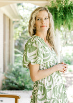 Close up of bubble short sleeves and v-neck on a cream dress with green palm leaves.