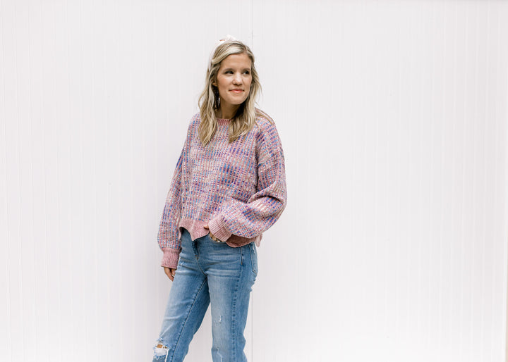 Model wearing a lilac striped sweater with an abstract background, long sleeves and a round neck. 
