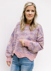Model wearing jeans with a lilac striped sweater with an abstract background and long sleeves. 