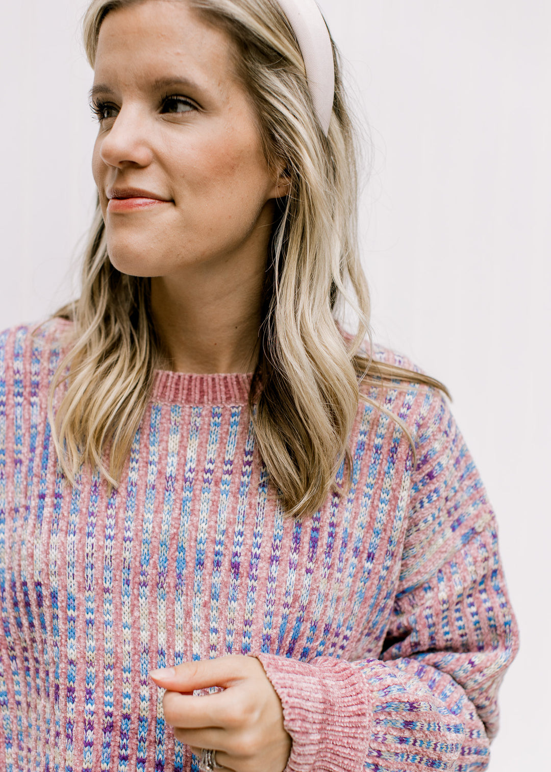 Close up of lilac stripes on an abstract blue, cream and purple background of a long sleeve sweater.