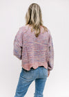 Back view of model wearing a lilac striped sweater with an abstract background and wavy hemline. 