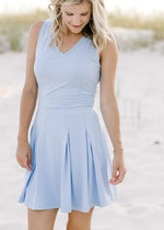 Model wearing a v-neck, sleeveless dress that hits above the knees and is light blue. 