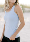 Close up view of model wearing a light blue racer back tank with a round neck. 