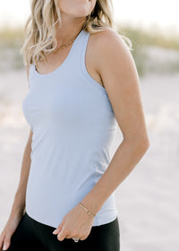 Close up view of model wearing a light blue racer back tank with a round neck. 