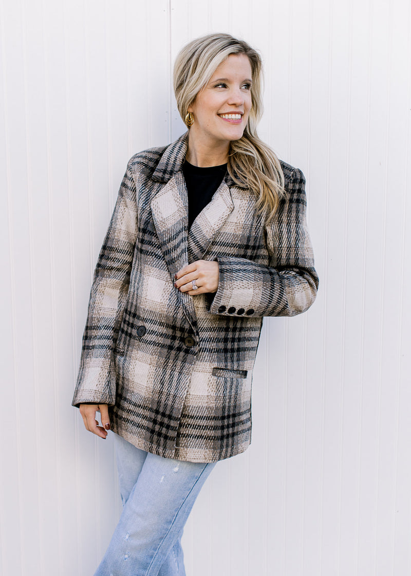 Model wearing a cream and black plaid jacket with button closure, collar and polyester material. 