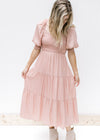 Model wearing a blush colored midi dress with a smocked bodice, v-neck and bubble short sleeves.  