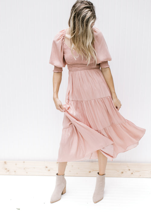 Model wearing booties with a blush, midi dress with a smocked bodice and bubble short sleeves.