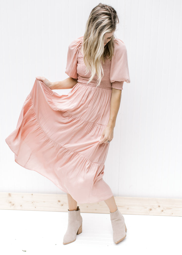 Model wearing a blush, lined midi dress with a smocked bodice, v-neck and bubble short sleeves.