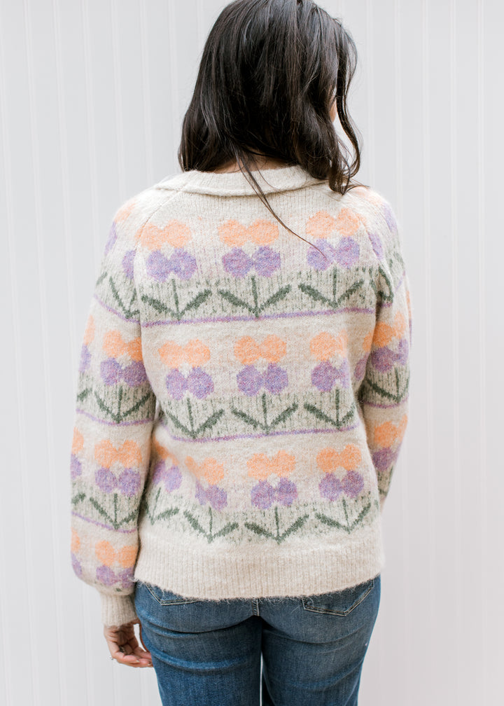 Back view of Model wearing a cream sweater with flowers, a round neck and long sleeves. 