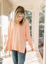 Model wearing a peach long sleeve top with side slits, an ultra soft material and ribbed detail. 