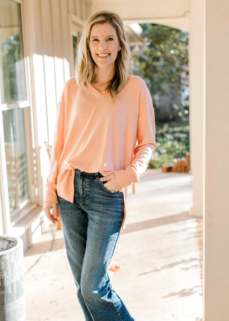 Model wearing jeans with a peach long sleeves and ribbed detail at the neck, cuff and hem. 