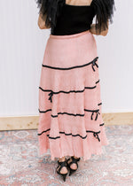 Back view of Model wearing a peach skirt with plisse bows, elastic waist and pleated fabric.