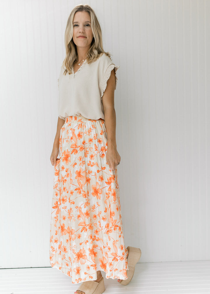 Model wearing cream top with a fully lined cream midi skirt with a white and peach floral pattern.