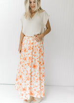 Model wearing a cream lined midi skirt with a white and peach floral pattern and an elastic waist.