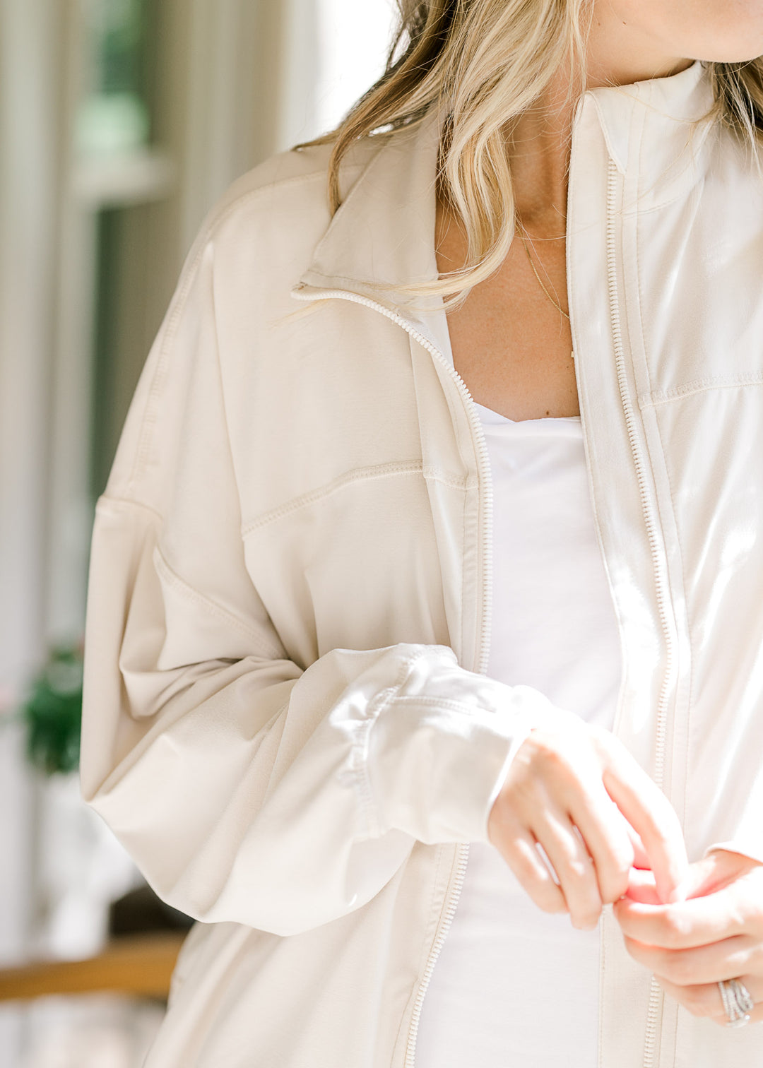 Model wearing a cream jacket with long sleeve with cuff and thumb hole, zipper and collar. 