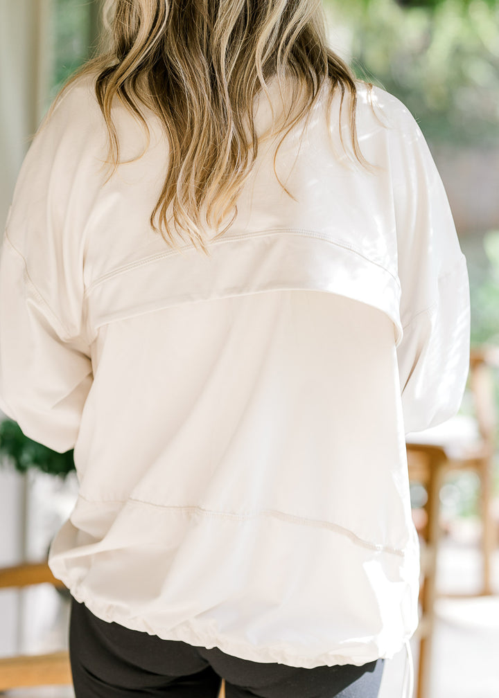Back view of breathable mesh on a cream long sleeve jacket with thumb holes and a zipper. 