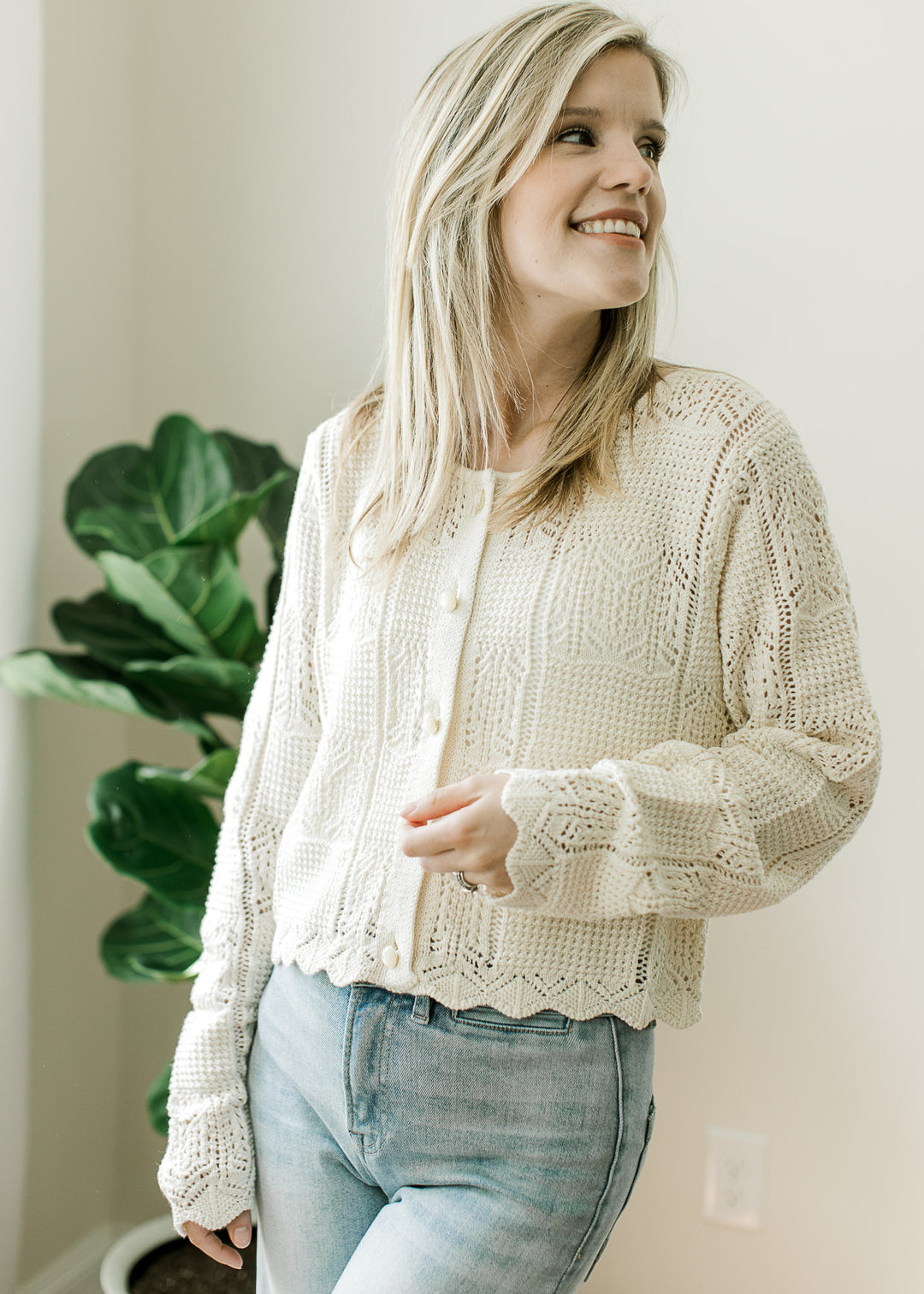 Model wearing a long sleeve cream cardigan with square knit pattern, pearl button front. 