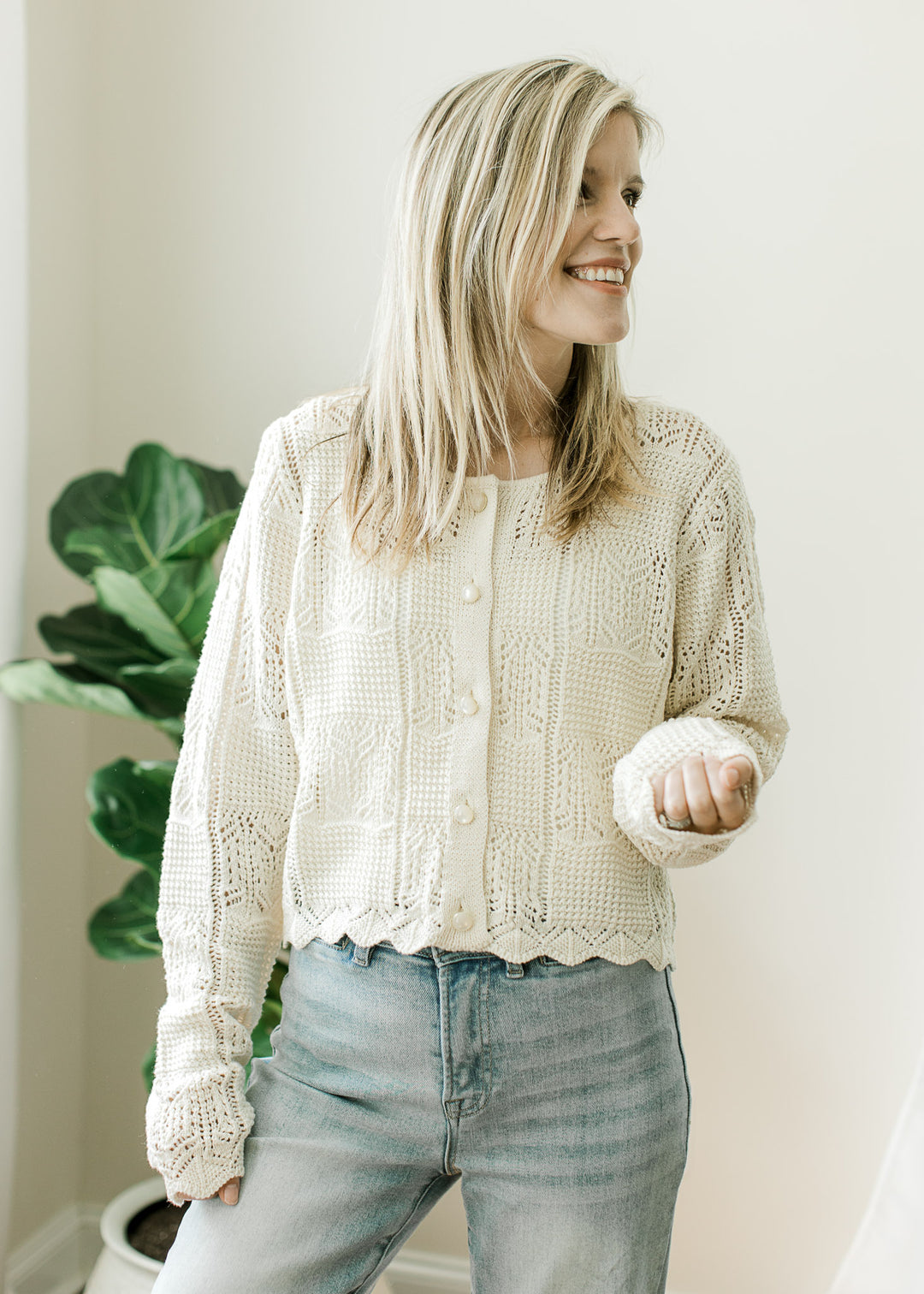 Model wearing a slightly cropped long sleeve cream knit cardigan with pearl button front. 