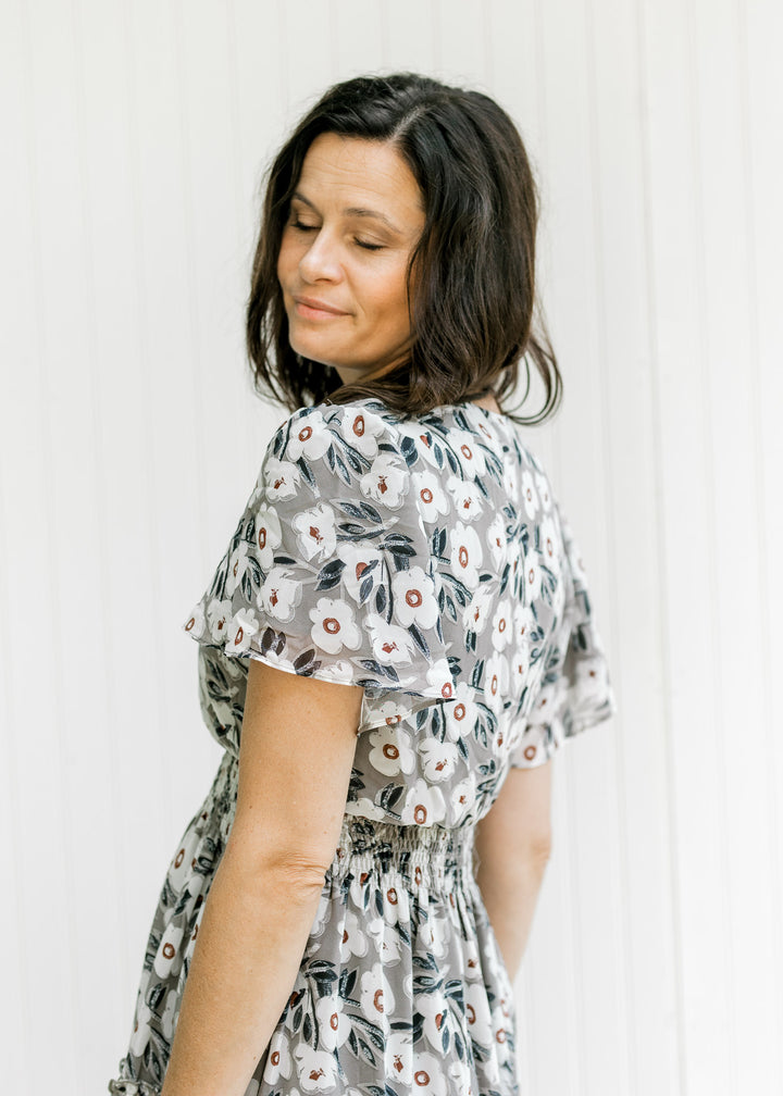 Close up view of flutter short sleeves and elastic waistband on the back of a gray and cream dress.