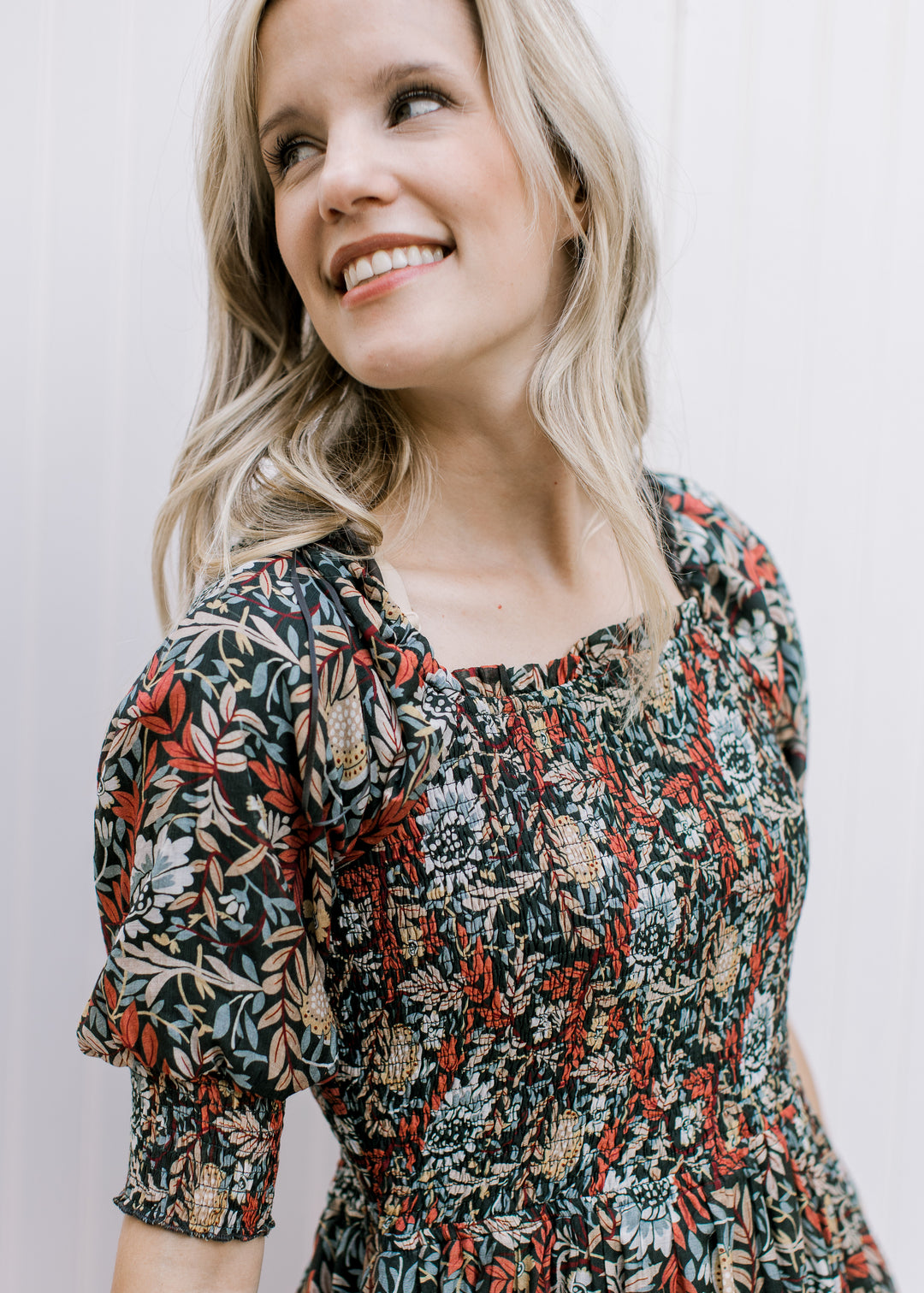 Close up of smocked bodice, square neck and short sleeves on a deep rust dress with floral. 