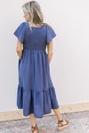 Back view of Model wearing a v-neck midi with a smocked bodice and flutter short sleeves.