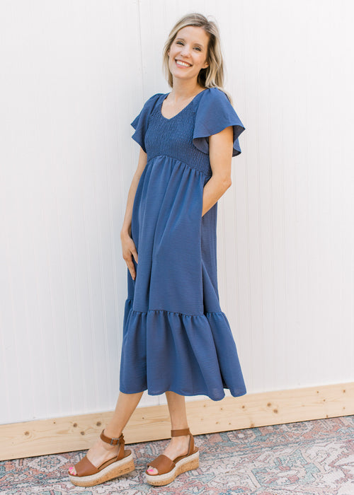 Model wearing heels with a v-neck midi with a smocked bodice and flutter short sleeves.