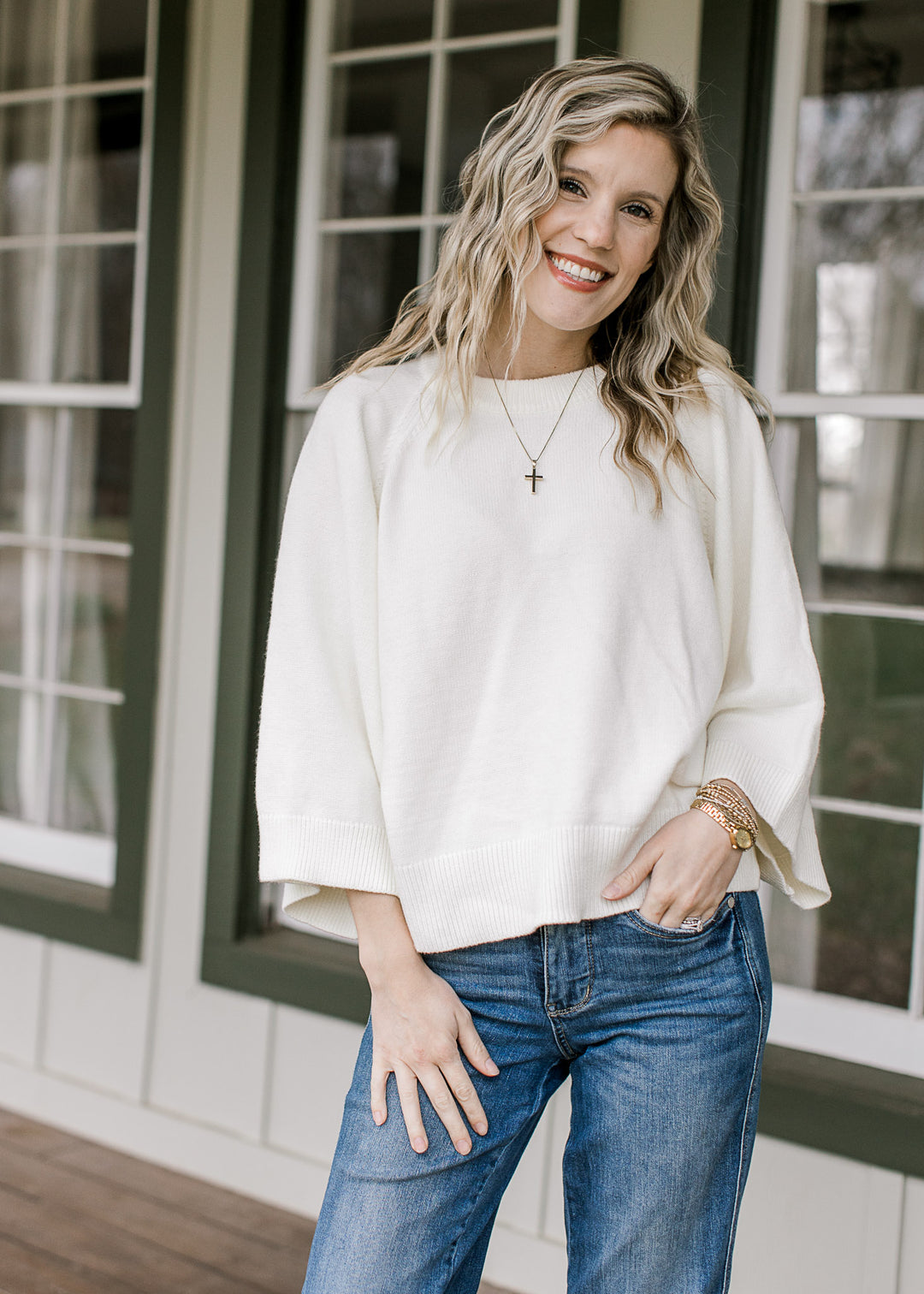 Model wearing a creamy white top with wide 3/4 sleeves, a round neck and a lightweight feel.